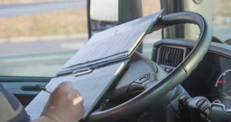 Closeup view of the hands of truck driver who is is writing in the documentation driver.